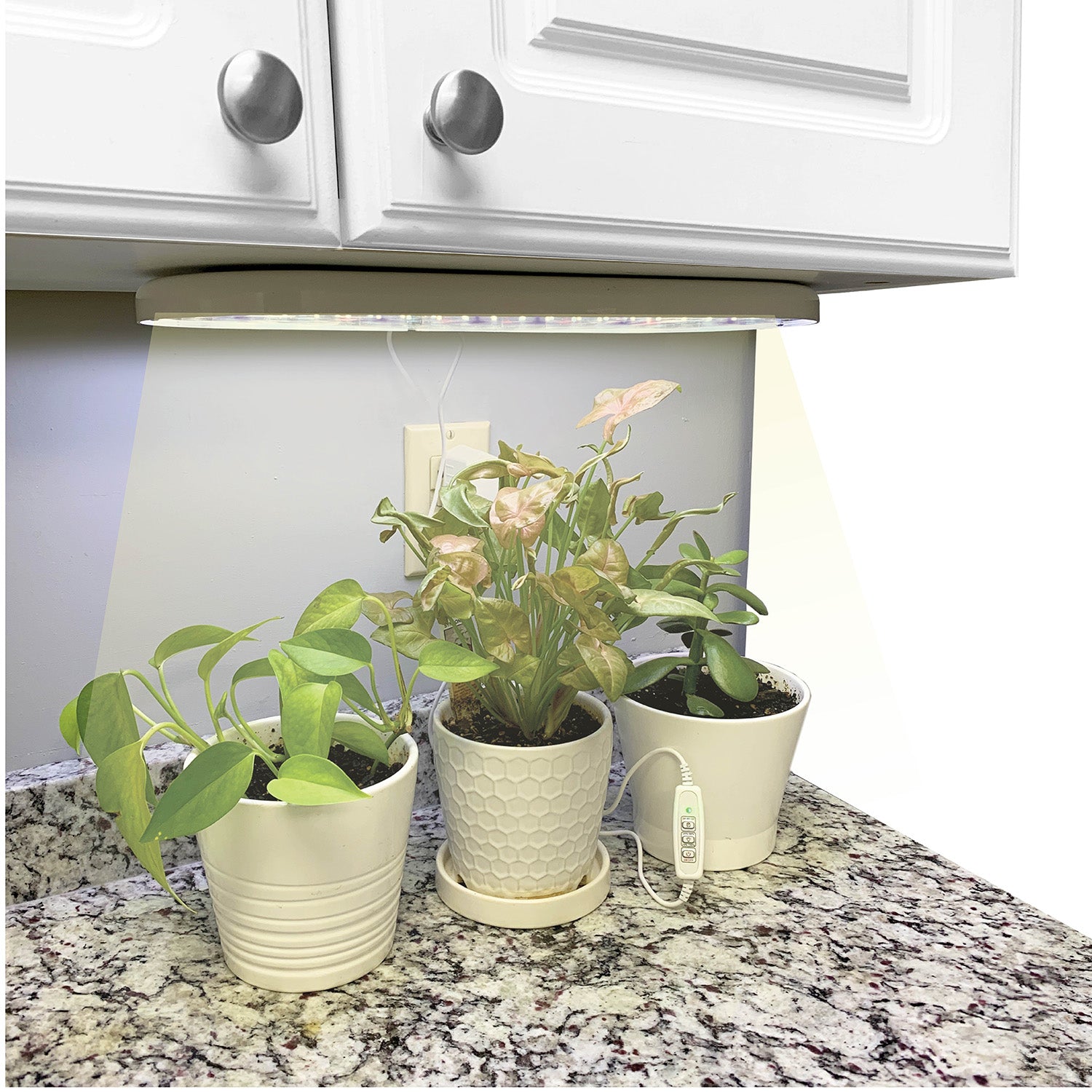 Indoor LED grow light mounted under a cabinet, with three potted plants below.